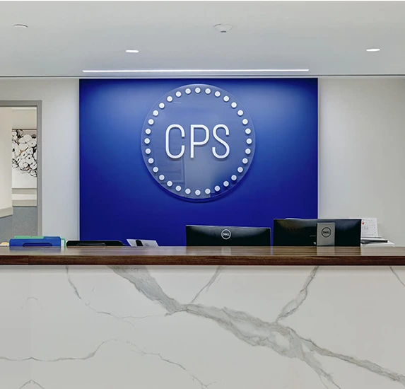 CPS reception desk with neon logo sign on blue wall and marble countertop